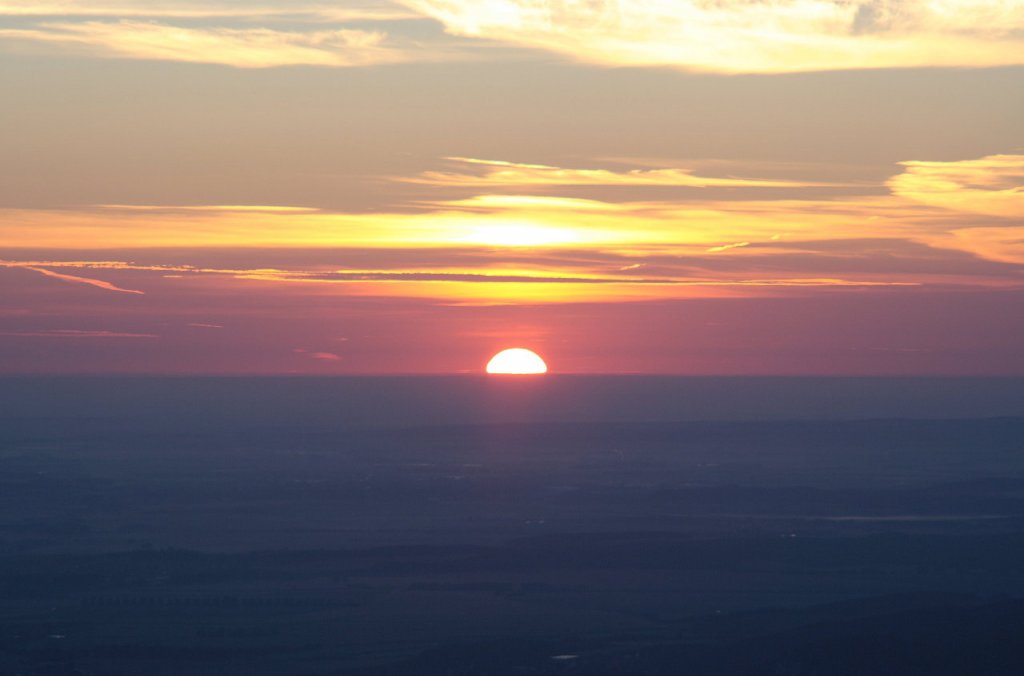 Sonnenaufgang auf dem Brocken; die Sonne hat sich zur Hlfte ber die Erdoberflche gehoben. Blick am frhen Morgen des 28.08.2012 von der Treppe des Brockenhauses ber das nordstliche Harzvorland