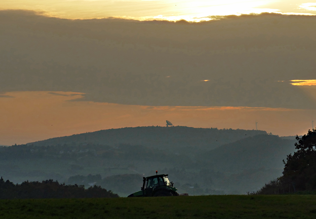Abenddämmerung in Richtung Eifel. Im Vordergrund verschwindet ein Traktor und auf dem Berg im Hintergrund  ist der  Astropeiler Stockert  (Nähe von Bad-Münstereifel)  zu erkennen. 23.10.2019 