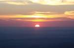 Sonnenaufgang auf dem Brocken; die Sonne hat sich zur Hälfte über die Erdoberfläche gehoben. Blick am frühen Morgen des 28.08.2012 von der Treppe des Brockenhauses über das nordöstliche Harzvorland