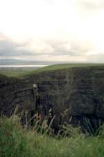 Der Blick ist gegen Sden gerichtet: im Hintergrund sieht man die Liscannor Bay, im Vordergrund teilweise die gut zweihundert Meter hohe Felswand der Cliff of Moher. Juni 2001 