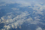 Blick aus dem Flugzeugfenster auf die schneebedeckten Alpenkämme.