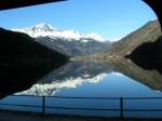 Landschaften Die Schnee bedeckten Bergspitzen spiegeln sich im klaren Wasser des Lago di Poschiavo am 24.12.06.