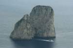 Inseln Ein Touristenboot hat grad eine der Faraglioni-Klippen vor Capri durchfahren.