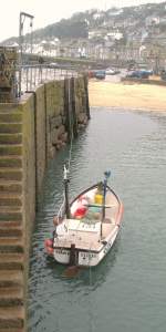 Ein Fischerboot an den Hafenmauern von Mousehole.