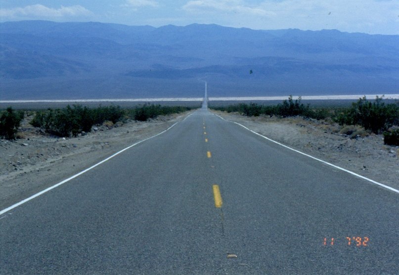 1992 im Death Valley Kalifornien USA. Schnurgerade fhrt die Strasse hinunter. Lange kann man schon das Wei des Salzsees erkennen