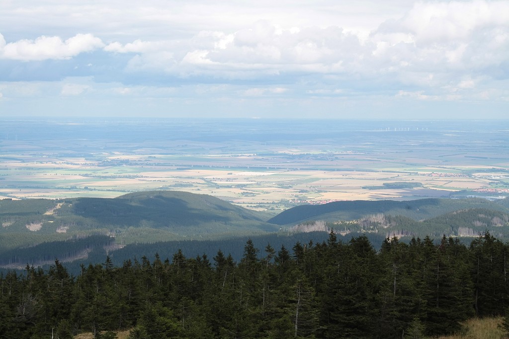 Am Nachmittag des 28.08.2011 auf dem Brocken; Sonnenlichtflecken und Wolkenschatten wandern ber das ndliche Harzvorland und die Norddeutsche Tiefebene; Blick von der Treppe des Brockenhauses ber Darlingerode am Harznordrand und den Huy Richtung Nordosten. In der Bildmitte am Horizont blitzt eine mchtige Industrieanlage, endlos weit entfernt, im Sonnenlicht...