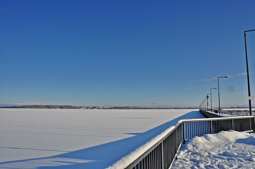 am Tag bevor  Daisy  kam, gefrorener Strelasund, schneebedeckt und eine klare Sicht auf den Rgendamm und ein Teilstck der Rgenbrcke vom Stralsunder Hafen aus mit Blick auf die Mole am 08.01.2010