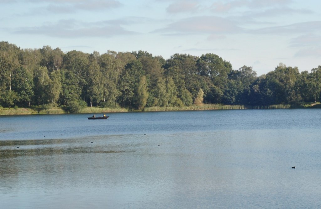 Blauer See am 19.09.2010, wo sich im Hintergrund ein Ruderboot mit Fischern befindet.