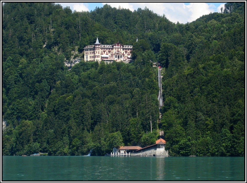 Der Brienzersee mit dem Grandhotel Giessbach, der dazugehrigen Standseilbahn und Schiffsanleger, von einem Schiff aus aufgenommen am 20.07.2010.