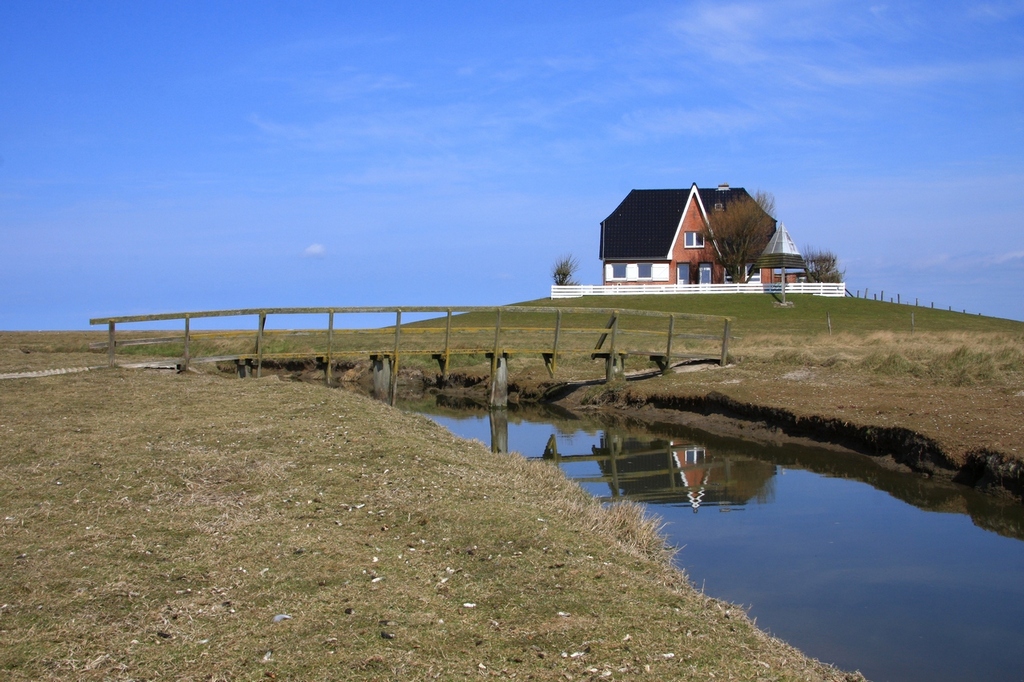 Die Amalienwarft auf Hallig Nordstrandischmoor ist Schule und Kirche zugleich. Im Gebude befindet sich auch noch die Dienstwohnung fr den Lehrer und unter dem Dreibein die Kirchenglocke. (24.04.2010)