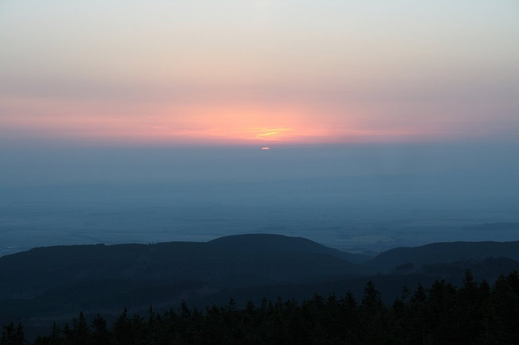 Die leuchtende Sonnenscheibe erscheint am Horizont in der Ferne; Blick am frhen Morgen des 19.06.2013 von der Treppe des Brockenmuseums auf dem Brockengipfelplateau...