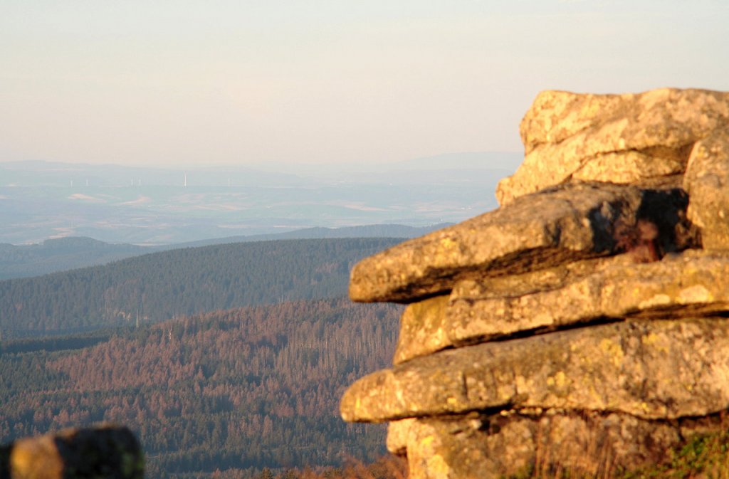 Die  Teufelskanzel  auf dem Brocken im ersten Morgensonnenlicht; Blick am frhen Morgen des 28.08.2012 vom Gipfelrundweg Richtung Sdwesten ber den sich groflchig erneuernden Wald der Achtermannshhe, den Rehberg, Berge des Sdharzes bis zum Dn, Eichsfeld und dem  Hohen Meiner  in den Kasseler Bergen (rechts am Horizont direkt neben dem Felsturm).