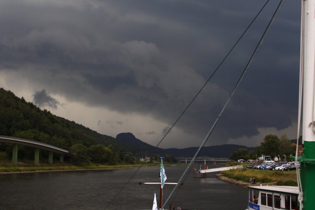 Durchzug einer Gewitterfront am 30.08.2012 ber dem Elbtal bei Bad Schandau, Bild 3: Und jetzt ist das Monster da! Mit gewaltiger Benwalze und Turbulenzen, welche ein Foto kaum wiedergeben kann! Das ganze Gebilde drehte sich deutlich entgegen des Uhrzeigersinns und die links im Bild hinter dem Berg aufsteigenden Wolkenfetzen brauchten nur wenige Sekunden bis sie die Wolkenbasis erreichten! Rechts hinten ist das Starkregen-/Hagelfeld zu erkennen. Ich glaube, der Anblick htte jeden  Storm-Chaser  begeistert! Solche Bilder kannte ich bisher nur aus dem Fernsehen von Berichten aus den USA! Wie ich spter erfuhr, hat dieselbe Unwetterzelle kurze Zeit nach dieser Aufnahme ber dem Zittauer Gebirge sogar einen Tornado hervorgebracht!!