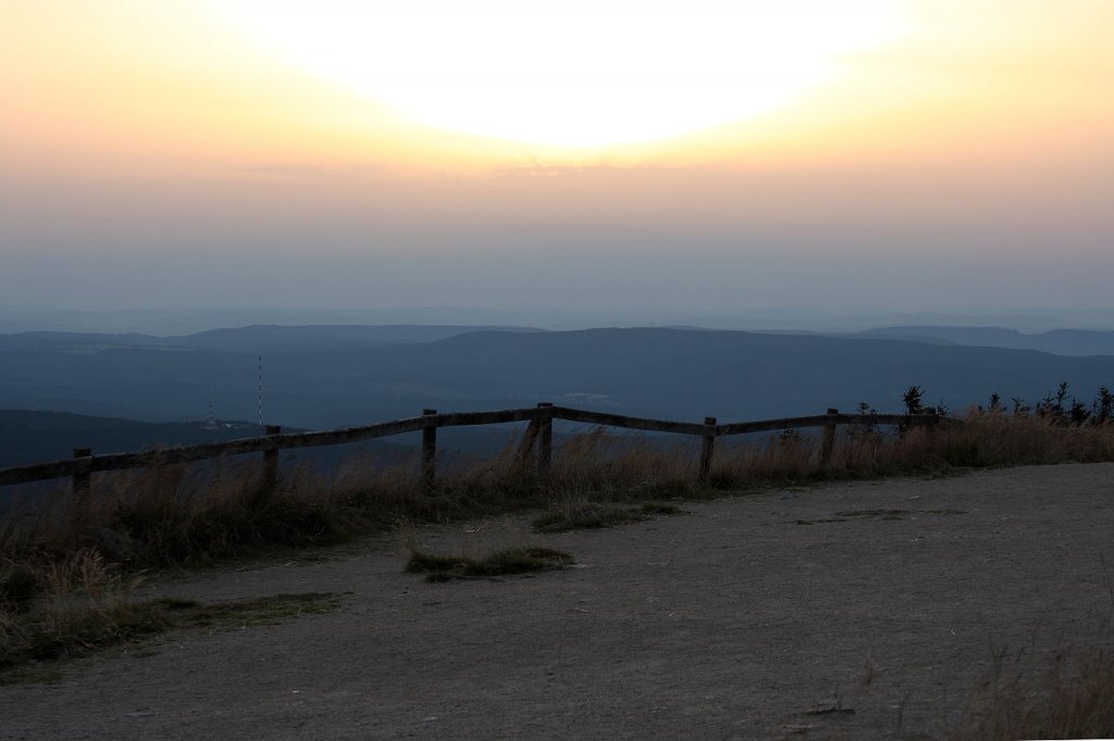 Letztes Abendsonnenlicht auf dem Brocken; Die Sonne ist dabei, hinter einer Wolkenwand in der Ferne zu versinken. Blick vom Gipfelrundweg am Abend des 19.08.2012 Richtung Westen ber den westlichen Oberharz bis zu den Weserberglandschaften am Horizont.