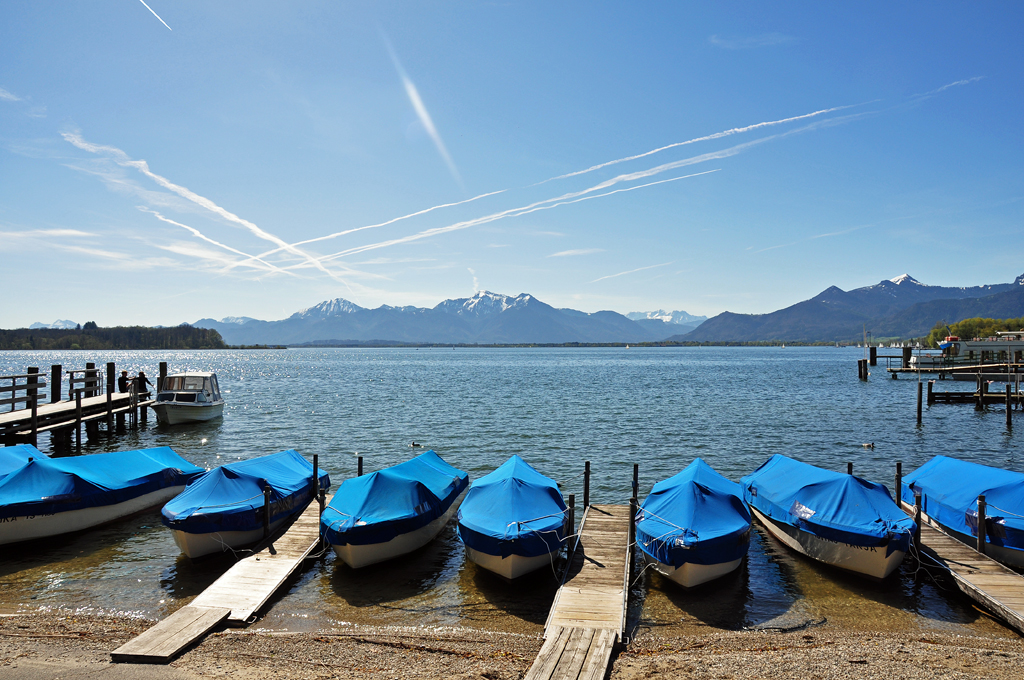 Mietboote am Chiemsee vor der Bergkulisse im Hintergrund warten auf Touristen - 27.04.2012