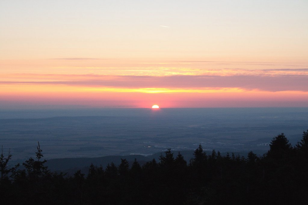 Sonnenaufgang auf dem Brocken: Die halbe Morgensonnenscheibe hat sich ber die Erdoberflche in der Ferne gehoben; Blick am frhen Morgen des 13.08.2012 vom Gipfelrundweg Richtung Osten ber Wernigerode und das nordstliche Harzvorland.