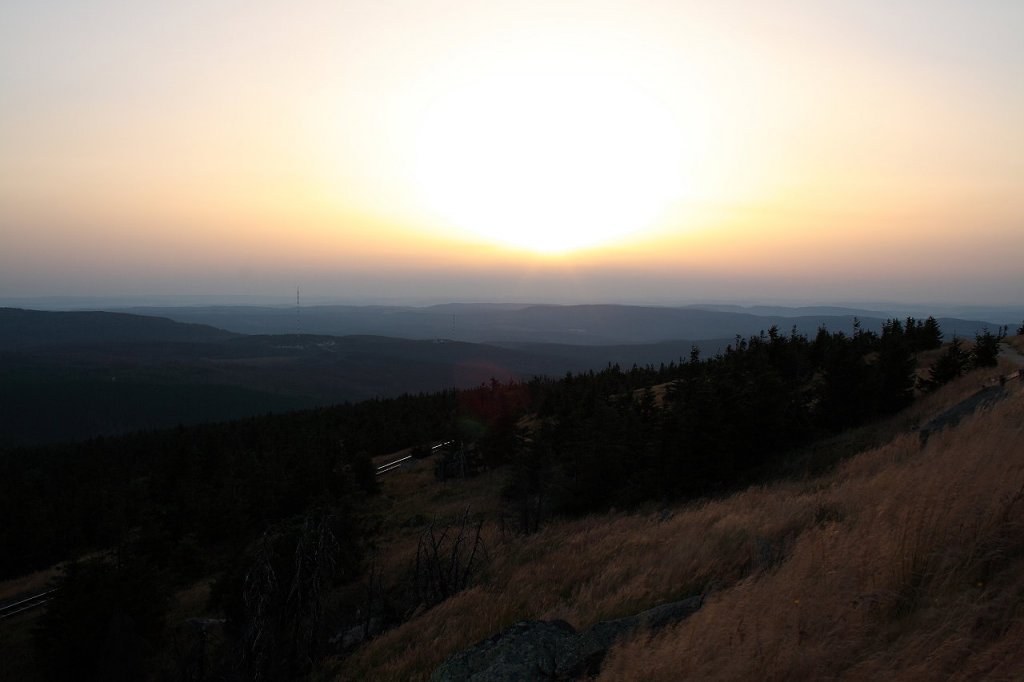 Sonnenuntergang auf dem Brocken; bald wird die Sonne hinter einer Wolkenwand in der Ferne versinken. Blick am Abend des 19.08.2012 vom Gipfelrundweg Richtung Westen ber Berge des Oberharzes bis zu den Weserberglandschaften am Horizont.