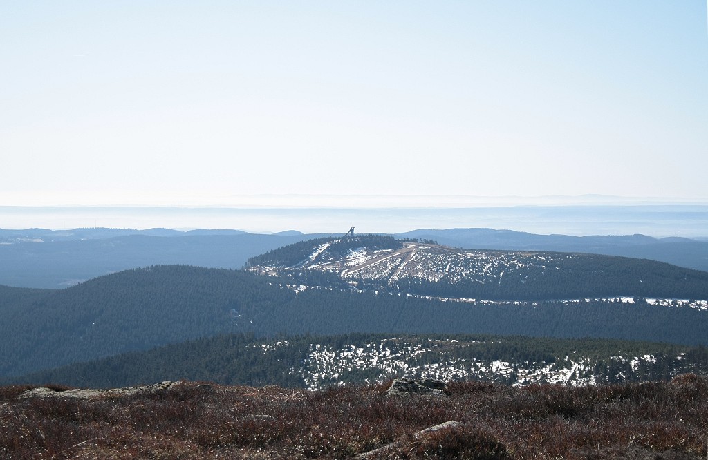 Vorfrhling auf dem Brocken: Blick um die Mittagszeit des 25.03.2012 vom Gipfelrundweg des Brocken Richtung Sden ber die z.T. noch von Schnee bedeckten Bergrcken des Knigsbergs und des Wurmbergs, den Sdharz, die Hainleite bis zum ber 100 km entfernten Mittelgebirge Thringer Wald, der unter dem Horizont aus einem Nebelmeer herausragt: Rechts erkennt man deutlich den Groen Inselsberg.