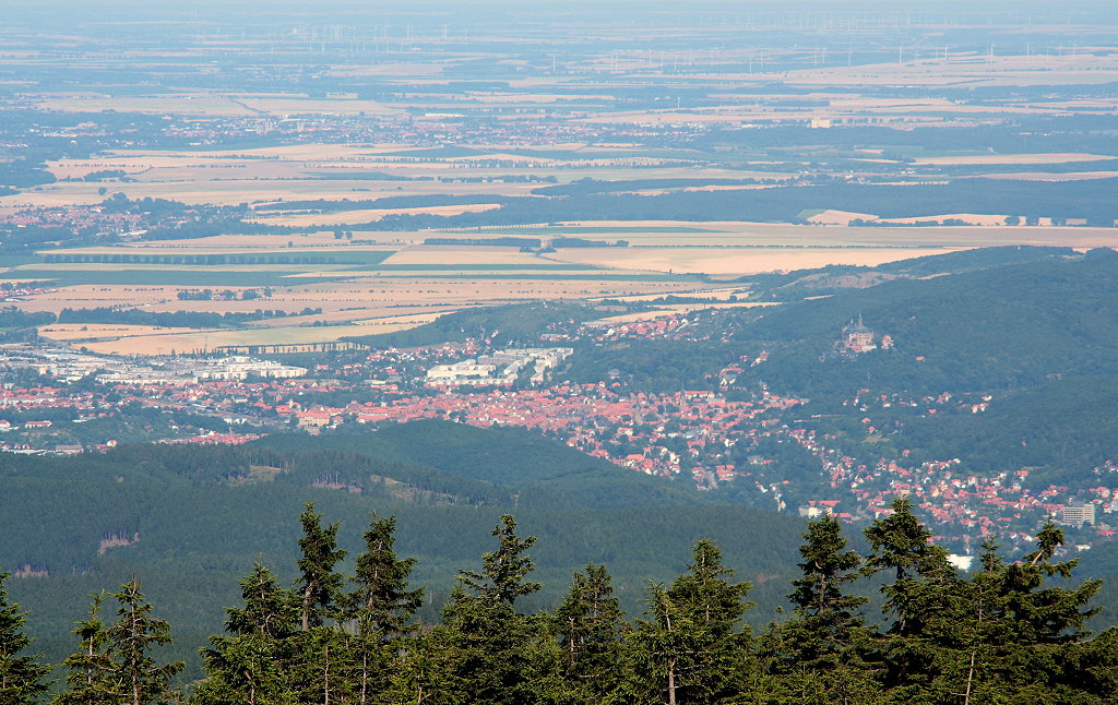 Weiter Blick vom Brocken Richtung Osten am Nachmittag des 21.07.2013: Unten am Harzrand liegt Wernigerode mit seinem Schloss auf dem Agnesberg, parallel dazu ist im oberen Bilddrittel die ca. 30 - 35 km entfernte Stadt Halberstadt zu sehen; deutlich erkennt man die Trme seiner mittelalterlichen Kirchen, die schlanken linken sind die vom gotischen Dom...