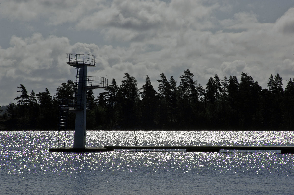 »Evedalsbadet« am See Helgasjön in Växjö im Gegenlicht. Växjö ist eingebettet in die schwedische Natur. Bereits in der Mitte der Stadt liegt der von schattigen Grünanlagen umgebene Växjö-See. Aufnahme: 17. Juli 2017.