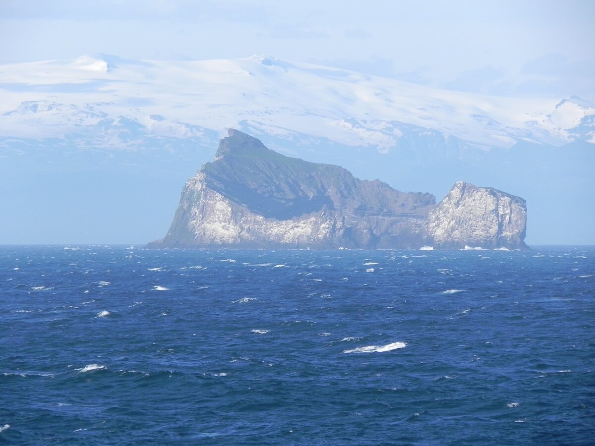 30 Inseln und Schären bilden den Archipel der Westmännerinseln vor der Südküste Islands. Erst vor 5.000 Jahren tauchten die letzten aus dem Meer auf. Im Hintergrund ist der sechtgrößte Gletscher Islands zu sehen, der Eyjafjellajökull. Im Juni 2010 sorgte der Ausbruch dieses Vulkans für große Probleme in der europäischen Luftfahrt.