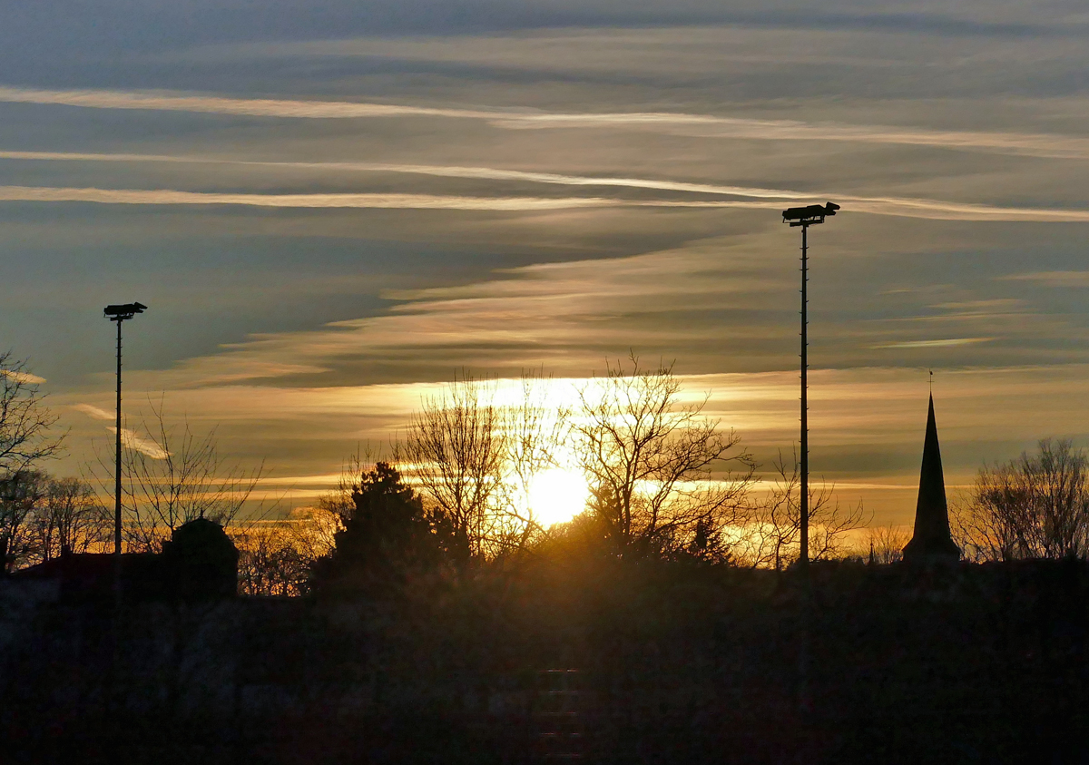 Abendstimmung/Sonnenuntergang mit Konturen von Fluglichtmasten und einem Kirchturm bei Euskirchen - 31.01.2020