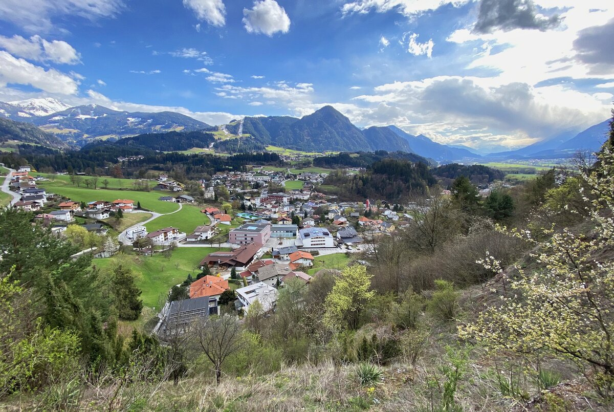 Blick über die Marktgemeinde Brixlegg im Tiroler Unterinntal. In der Bildmitte sind das Schulzentrum, das Freischwimmbad sowie das Wohn- und Pflegeheim erkennbar. Im Hintergrund das Bergpanorama des Alpbachtals. (10.04.2022)