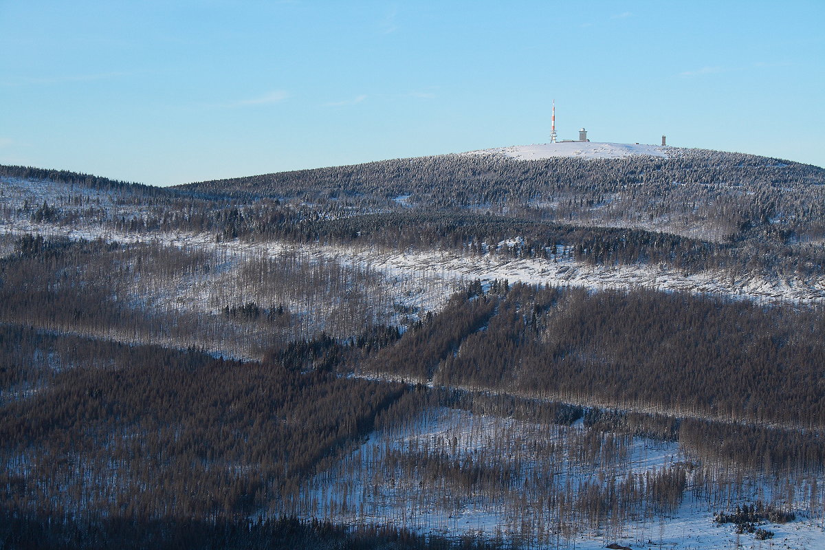 Blick vom Wurmberg auf den Brocken am frühen Abend des 14.02.2021; man erkennt links den riesigen Antennenturm der Telekom, rechts daneben den Turm des Hotels  Brockenherberge , daneben die Wetterwarte, alle drei Gebäude noch aus DDR-Zeiten, als der gesamte Gipfelbereich für Besucher gesperrt war... 