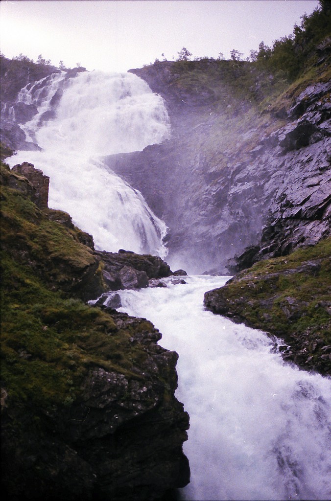 Der Kjosfossen ist ein sagenumwobener Wasserfall in Norwegen. Er gehört zur Gemeinde Aurland in der Provinz Sogn og Fjordane und liegt direkt an der Flåmsbahn. 1951 wurde in der Nähe des Wasserfalls ein Halteplatz für die Bahn errichtet, damit die Reisenden den Zug verlassen können, um den Wasserfall zu besichtigen. Aufnahme: Juli 1985 (digitalisiertes Negativfoto).