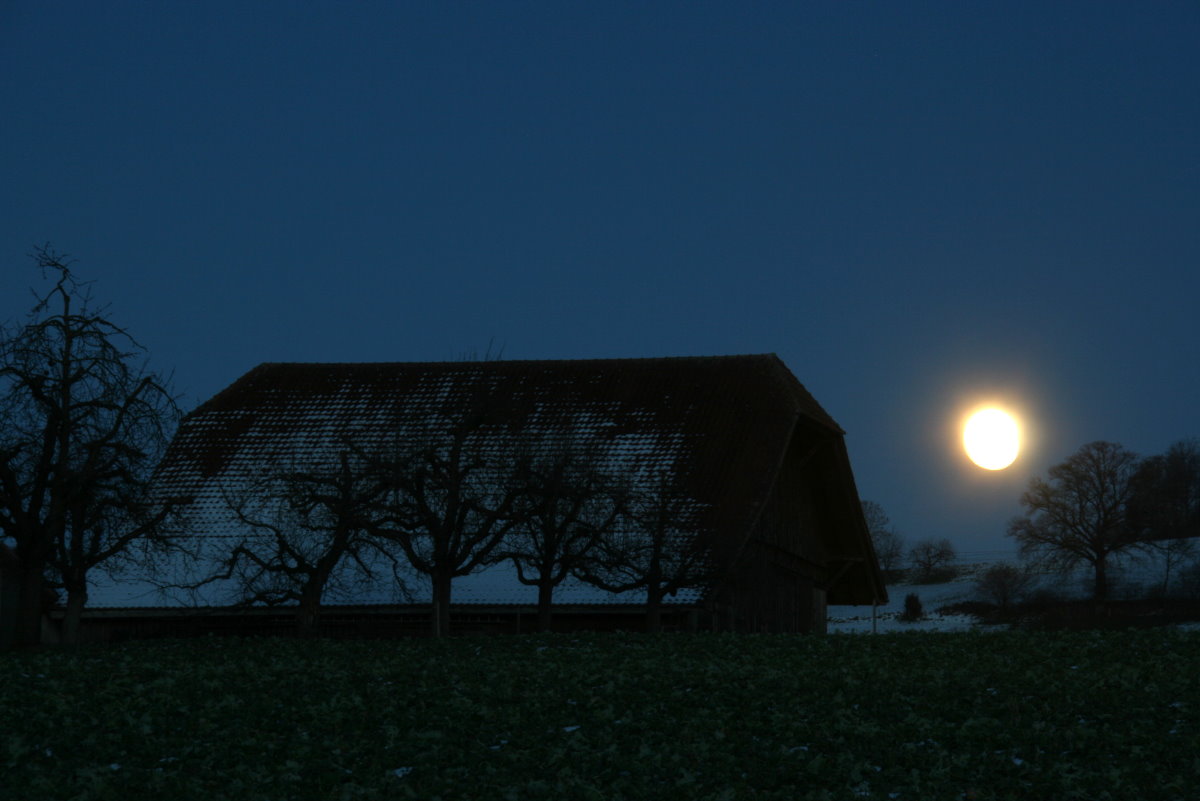 Der Vollmond vom 23.01.2016 ist neben einem Gehöft im Emmental aufgegangen.