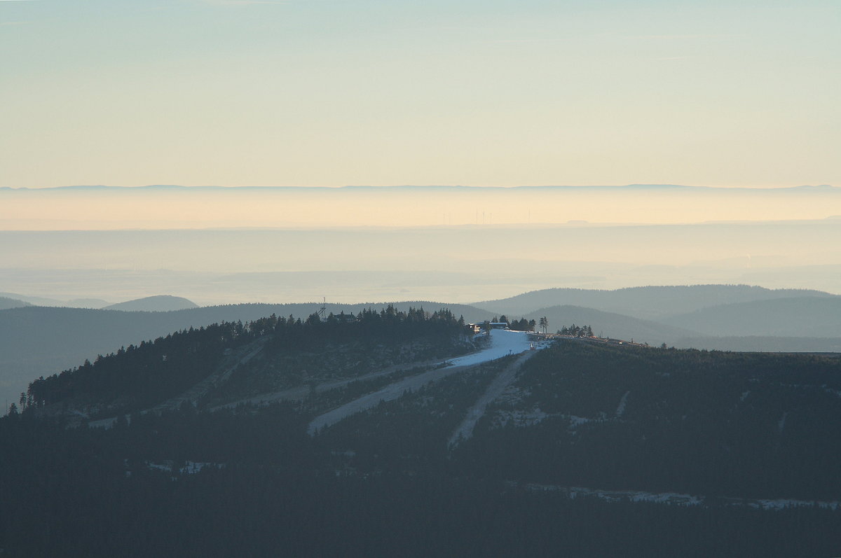 Dezemberabend am 05.12.2016 auf dem Brocken; über dem dunklen Gipfel des Wurmbergs ragen im Süden in der Ferne die höchsten Berge des Thüringer Walds am Horizont aus einem Nebelmeer...