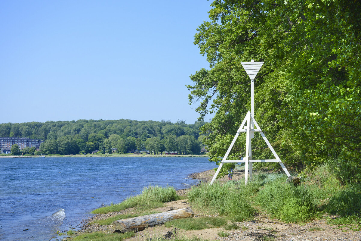 Die Küste bei Kollund Skov auf der dänischen Seite der Flensburger Förde. Im Hintergrund links ist Wassersleben auf der deutschen Seite der Grenze zu sehen. Aufnahme: 11. Juni 2023.