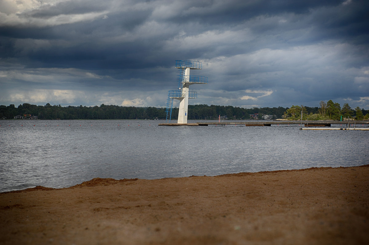 Die Sprungturm am Strand von »Evedalsbadet« am See Helgasjön in Växjö. Evedal ist ein großes Freizeitgebiet am Ufer des Helgasjön, nördlich von Växjö. Hier gibt es schöne Badestrände, einen kleinen Bootshafen mit Verleih, eine Minigolfanlage, Restaurants, Spielplätze, Möglichkeiten zum Angeln und viele Wanderwege.

Aufnahme: 17. Juli 2017.