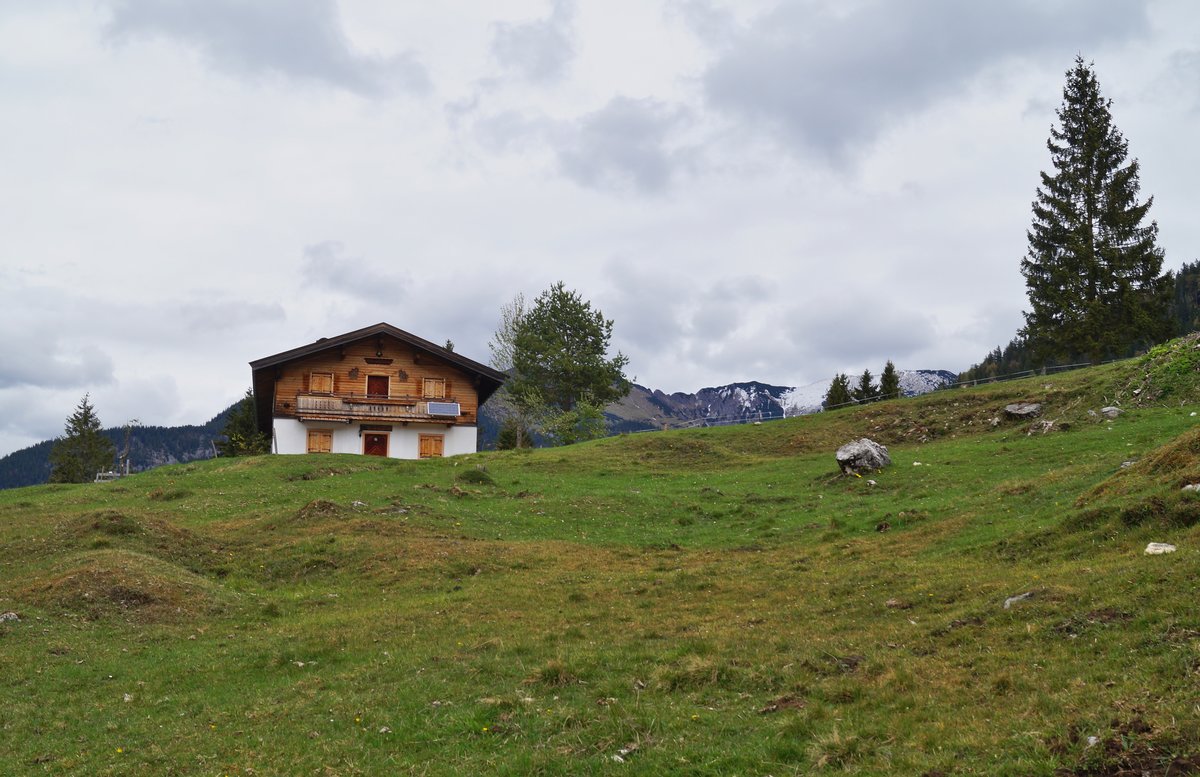 Eine Almhütte lädt zur Rast ein in den Brandenberger Alpen nahe der Grenze zu Deutschland (Bayern). Im Hintergrund die noch immer leicht verschneiten Kalkalpen. 01.05.2020.