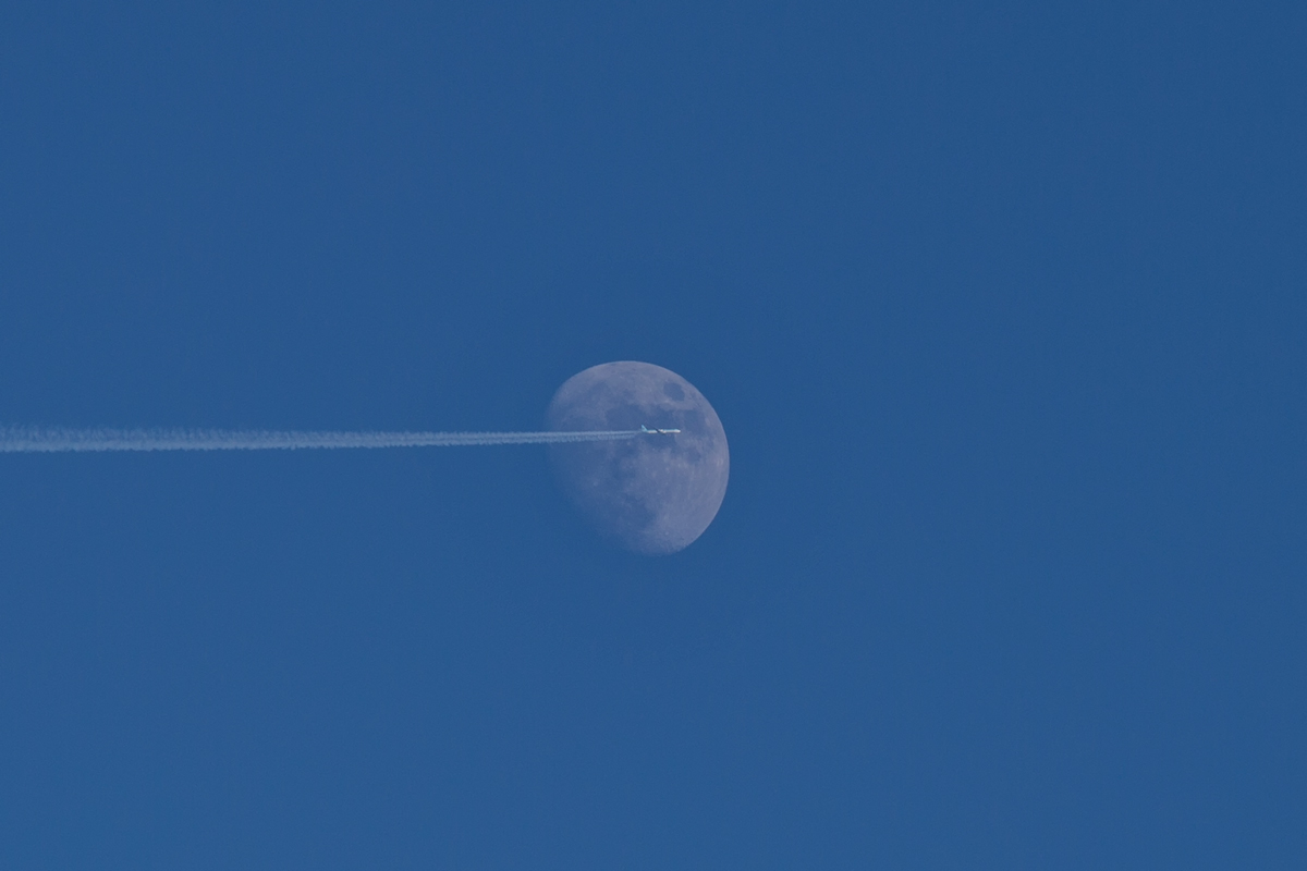 Flugzeug mit Kondensstreifen vor zunehmenden Mond. - 12.03.2014