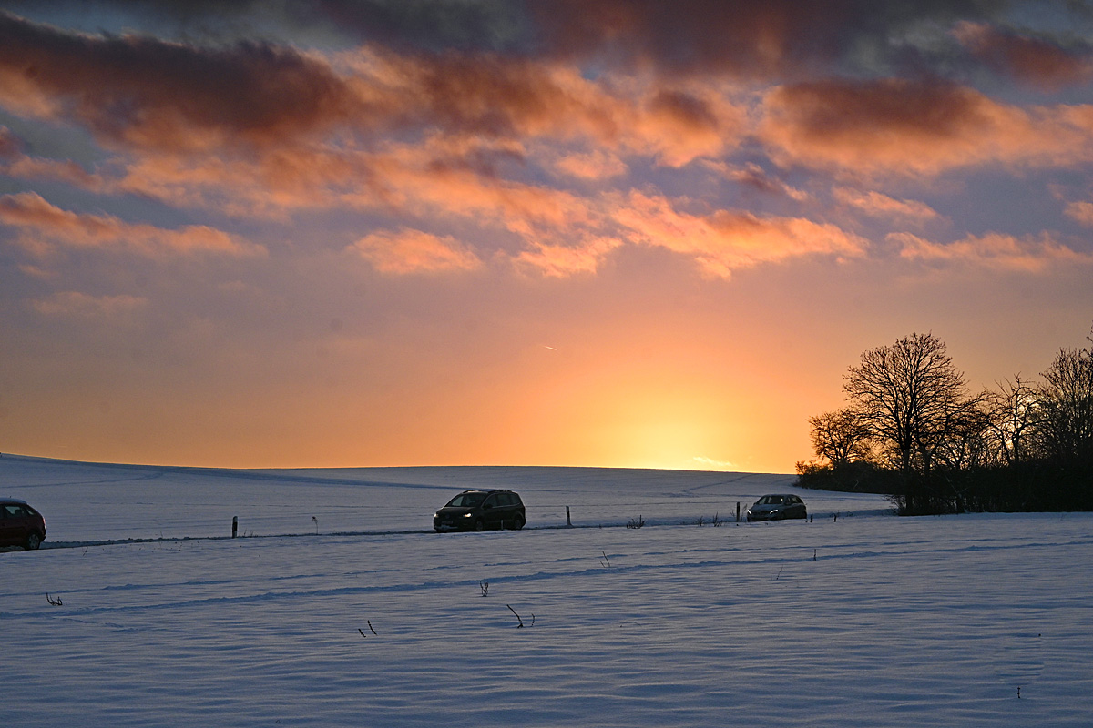 Heimkehrende Pendler bei Sonnenuntergang durch schneebedeckte Landschaft in der Eifel - 19.01.2024