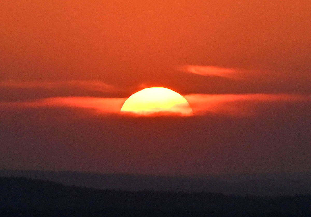 Langsam verschwindende Sonne hinter Dunst und Wolken am Horizont - 31.03.2021