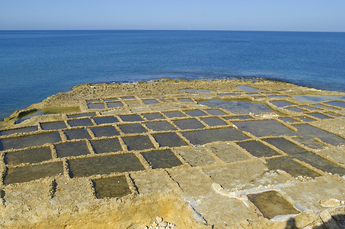 Salzpfannen auf Gozo. Aufnahme: Oktober 2006. Die Becken an der Nordküste Gozos wurden bereits von den Römern aus dem Fels gemeißelt und dienen bis in heutige Zeit zur Salzgewinnung.Das Meerwasser der rauhen See fließt in die Mulden, wo es anschließend nach und nach verdunstet. Zurück bleibt eine Salzschicht, die abgeschöpft wird.