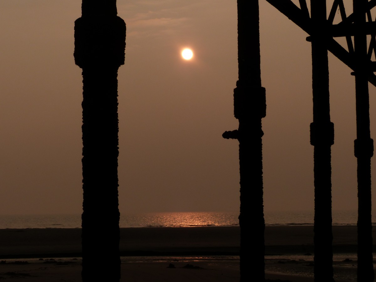 Sonnenuntergang am Blackpool Central Pier - bei Ebbe konnte man unter dem Pier durchlaufen, dabei ergab sich dieses Sonnenuntergang-Fotomotiv. Sonnenuntergänge alleine finde ich immer schwierig zu fotografieren. Zwar sehen viele Fotos gut aus, dennoch sind sie oft austauschbar. Daher nutze ich gerne Bildelemente im Vordergrund, um das Sonnenuntergangsfoto zu gestalten. 17.3.2015