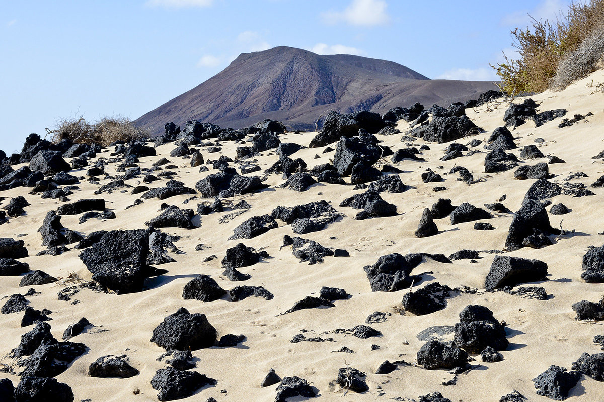 Vulkansteine in den Wanderdünen südlich von Corralejo auf der Insel Fuerteventura in Spanien. Aufnahme: 18. Oktober 2017.