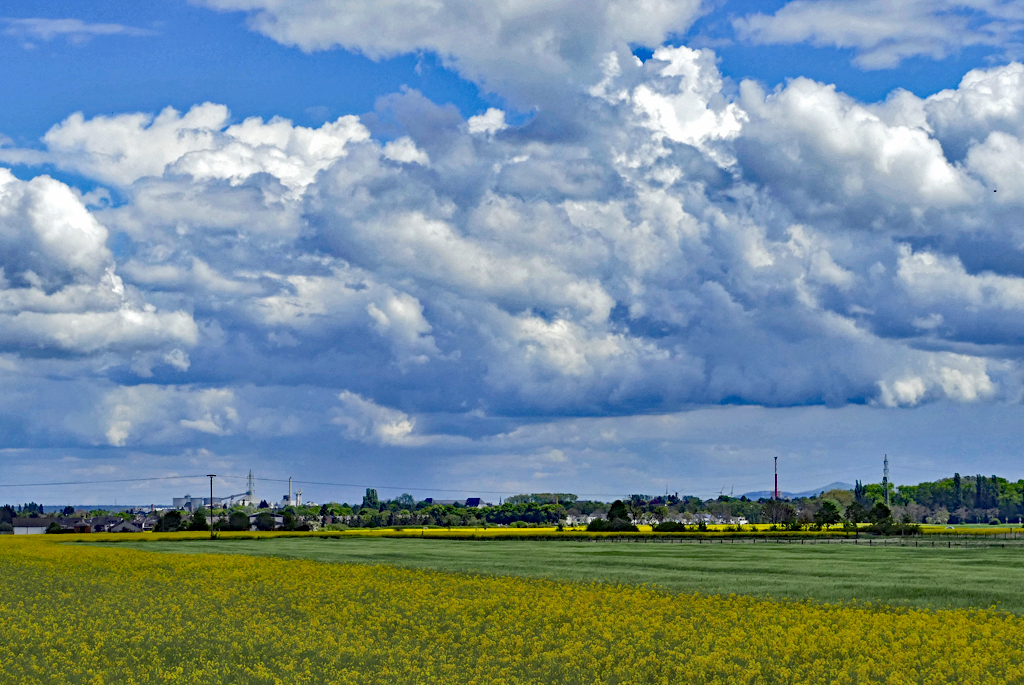 Wolken, Wald und Felder im Frühling in der Voreifel. Rechts im Bild zwischen Kamin und Hochspannungsmast noch ein bißchen Siebengebirge in 35 km Entfernung. 12.05.2017