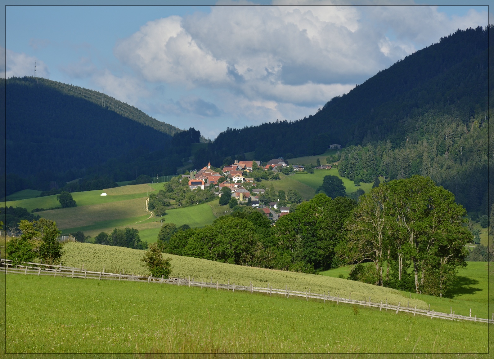 Blick vom Chemin du Pasteur Frêne im Petit Val hinüber nach Souboz. Was ein zauberhafter Ort der Ruhe, rechts die Hänge des Moron, für mich Anwärter auf den Ort mit dem besten Käse der Schweiz... Mitten in diese Ruhe platzten zwei Wandererinnen, die auf ihrem Weg waren, dem nach Santiago der Compostella. An diesem Abend von Münster gestartet kurz vor ihrem Tagesziel, der Abtei Bellelay. Die Hochebene der Freiberge liegt im Rücken des Betrachters. Sornetan, Juli 2021.