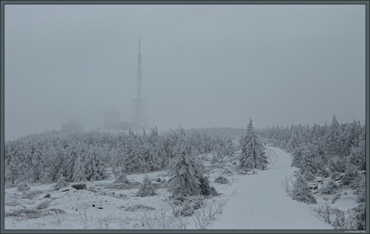 Mit Schnee und Eis bedeckt zeigt sich am 26.11.2023 der Brockengipfel. Nur schemenhaft sind die Sendeanlagen auf dem Berg durch Wolkenschwaden zu erkennen.