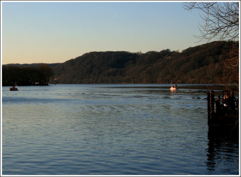 Blick ber den Baldeneysee in Essen-Heisingen. Whrend die DLRG trainiert, sitzen andere gemtlich in der Sonne. ber dem rechten Boot ist oben im Wald das Lokal  Schwarze Lene  zu erahnen. Es liegt direkt unterhalb der Neu-Isenburg (Ruine) - von der Terasse aus hat man einen herrlichen Ausblick ber den Baldeneysee und das Umland. 