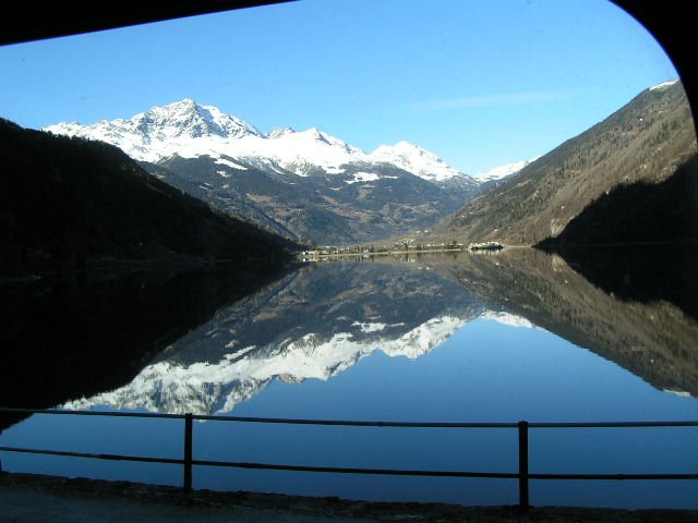 Die Schnee bedeckten Bergspitzen spiegeln sich im klaren Wasser des Lago di Poschiavo am 24.12.06.