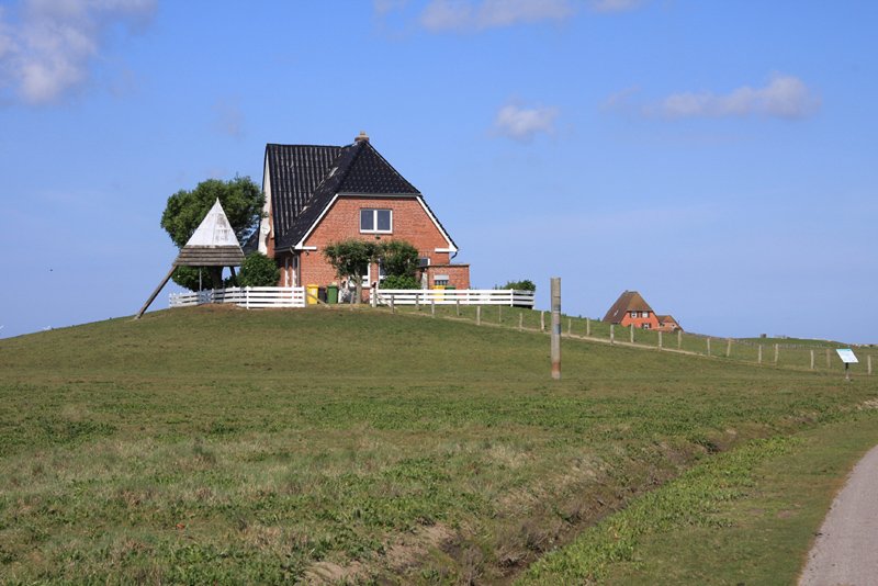 Hallig Nordstrandischmoor - 14.06.2008 - Die Amalienwarft oder Schulwarft, hier befinden sich Grund- und Hauptschule der Hallig. Sie dient auch als Wohnung des Lehrers und Kirche, die Glocke hngt unter der dreieckigen berdachung links vom Haus. Vor der Warft der Sturmflutpfahl. 