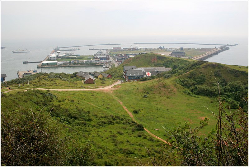 Im Vordergrund der Sprengungskrater  Mittelland  auf der Insel Helgoland. Im April 1947 wollten die Briten sämtliche militärische Anlagen in die Luft sprengen. Es handelte sich um die größte nichtnukleare Sprerrung bisher mit 6700 Tonnen Sprengstoff. Nur im Bereich des heutigen Mittelland hielt die Insel diesem Gewaltakt nicht stand und der dortige Teil des Oberlandes flog in die Luft. 1952 wurde die Insel an Deutschland zurückgegeben und wieder besiedelt. Im Hintergrund der Südhafen, in Bildmitte kann der Halunder Jet (Hochgeschwindigkeitskatamaran) erkannt werden. 

16.07.2007 (M)