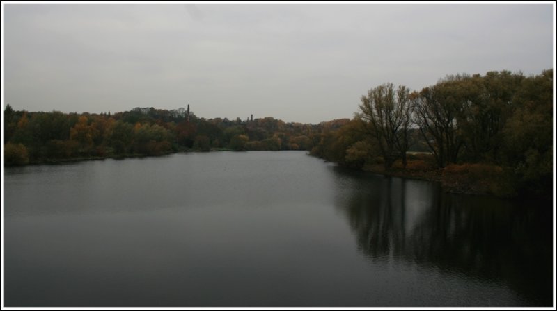 Mlheim-Ruhr - Blick auf die Ruhr von der Fugngerbrcke am Walzenwehr. Links zwischen den Bumen ist der Kamin der Lederfabrik Lindgens (Kassenberg) zu sehen, rechts die Ruhrinsel. Kmpfe leider noch mit der Helligkeit bei Landschaftsaufnahmen im Vollautomatik-Modus meiner neuen Kamera.