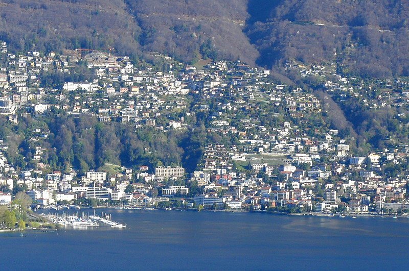 Piazoggna - Blick ber den Logo Maggiore auf Muralto und Minusio (unten) und Orselina (oben). Ganz links ist der neu angelegte Yacht-Hafen von Locarno sichtbar. (Teleaufnahme ce. 8 - 9 km Entfernung) Foto vom 07.04.2008