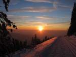 Gleich wird die Sonne hinter den Vogesen verschwinden. Sonnenuntergang auf einem Berg im winterlichen Schwarzwald in der Nhe der Hornisgrinde und dem Mummelsee.